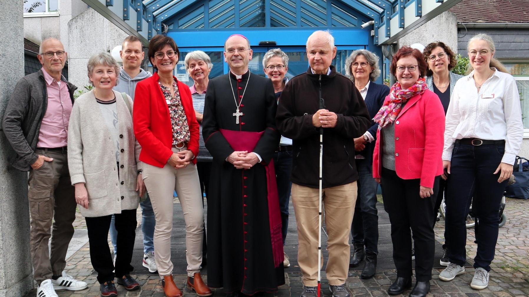 Weihbischof Robert Brahm (Mitte) tauscht sich mit ehrenamtlichen „Grünen Damen und Herren“ im DRK Krankenhaus Kirchen aus. Es fehlen auf dem Foto weitere langjährige Ehrenamtliche.