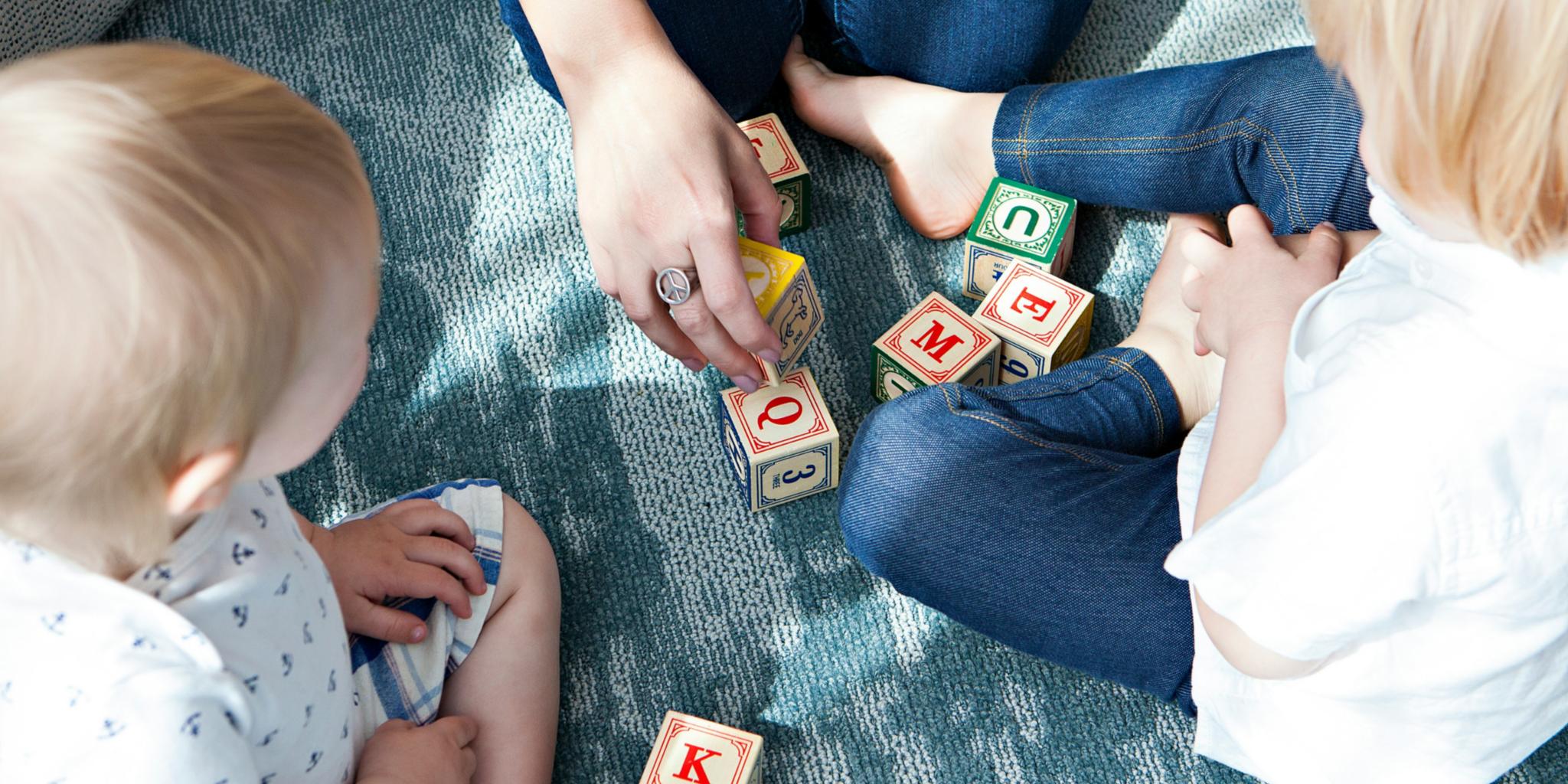 Man sieht 2 Kinder beim Spielen mit Buchstabenwürfeln