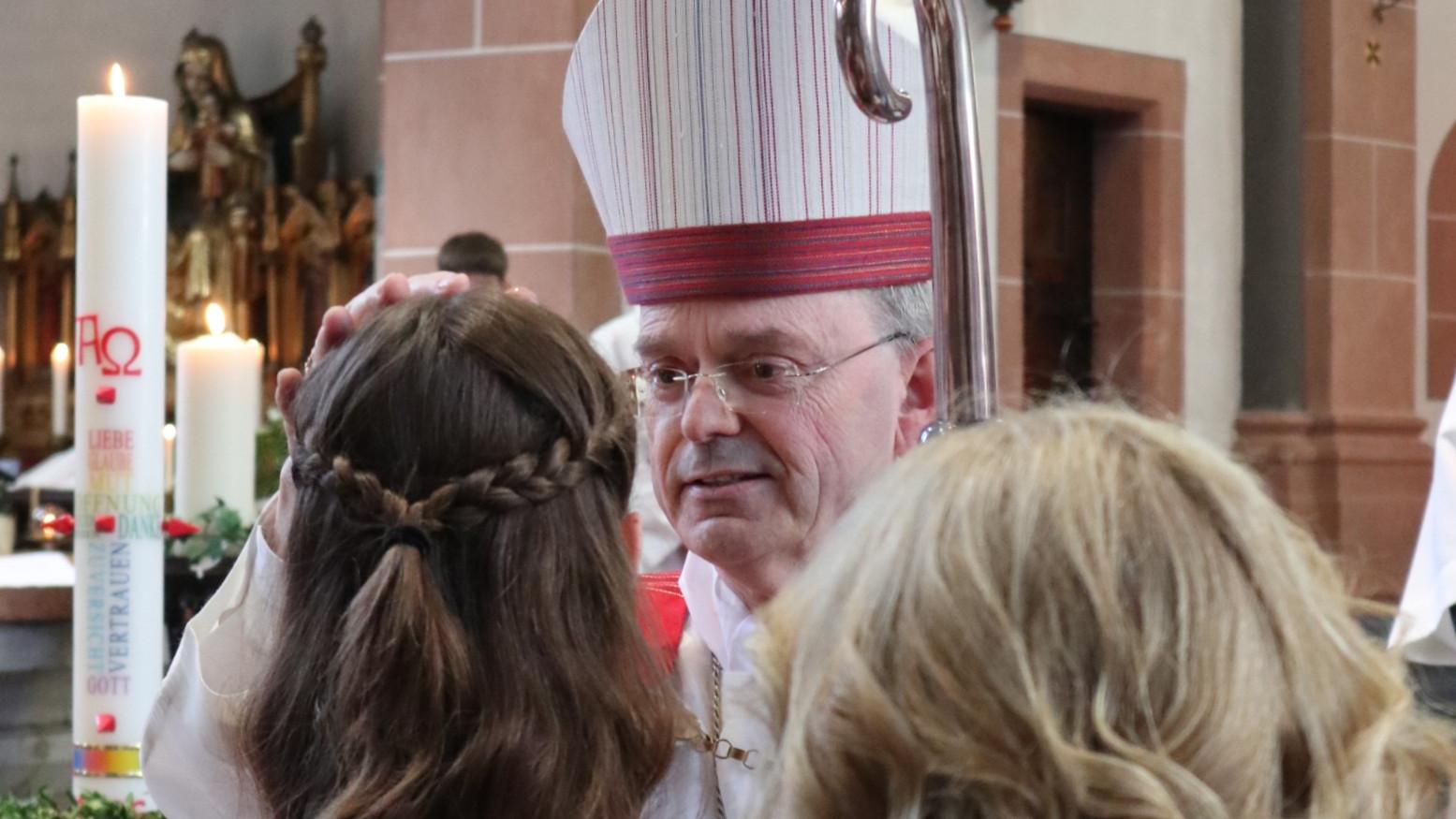Weihbischof Brahm spendet einer jungen Frau das Sakrament der Firmung