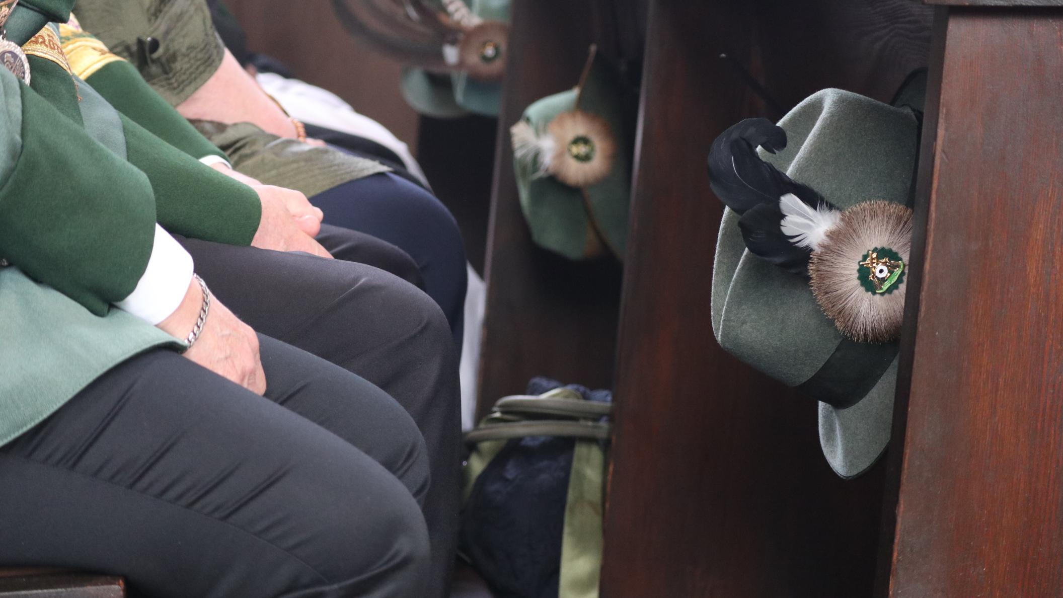 Schützenhüte hängen an einer Kirchenbank.